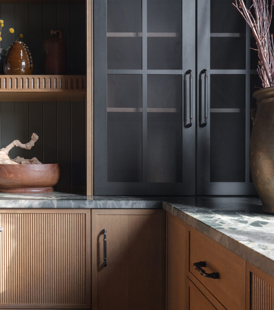 Pembroke Inset quarter-sawn cabinetry in Sand custom stain with decorative metal mesh cabinet doors by Mouser Cabinetry.