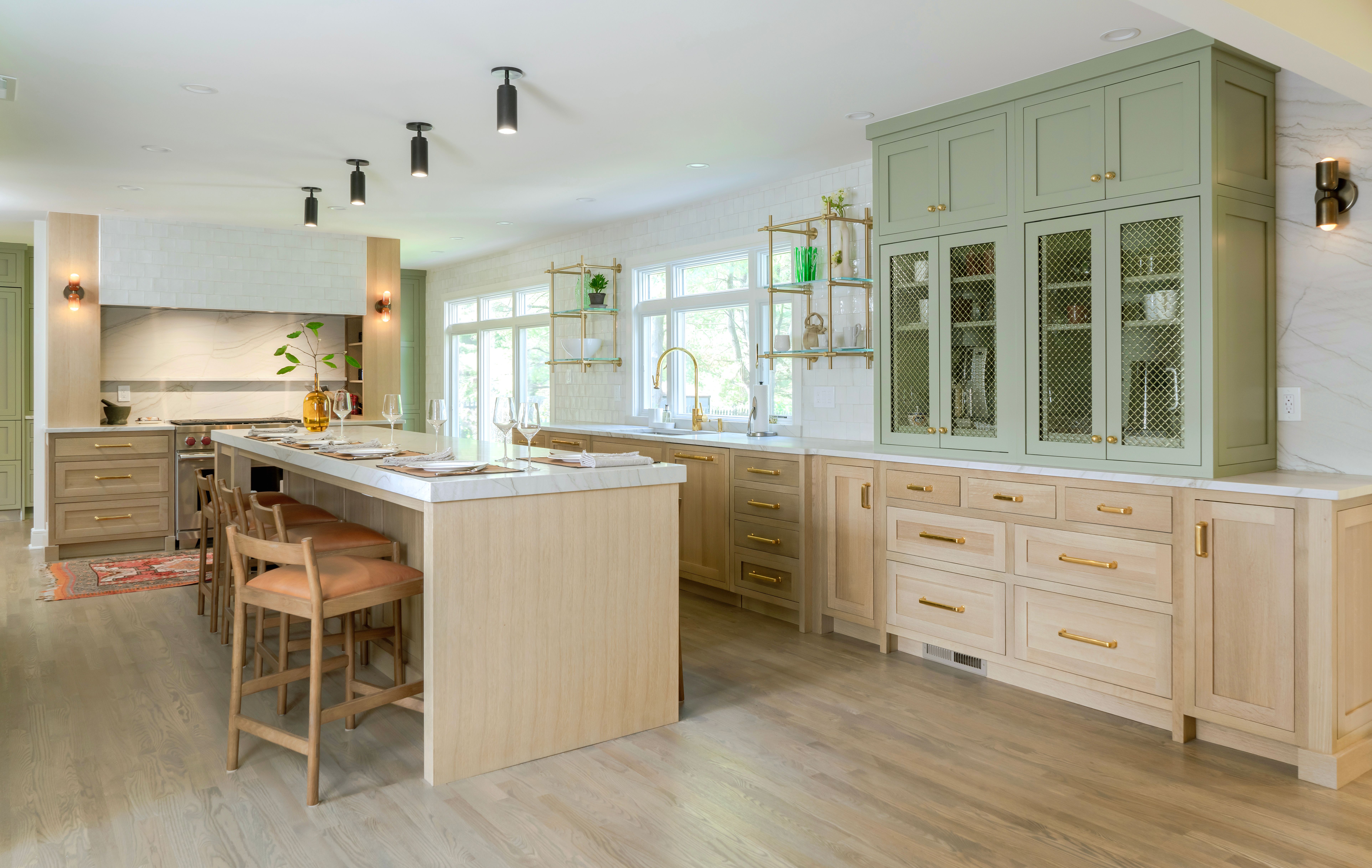 White oak kitchen cabinetry with green upper cabinets and brass hardware in a modern kitchen remodel.