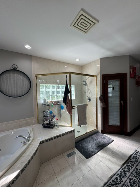 Original master bathroom shower before renovation in Woodstock, IL featuring a brass framed shower enclosure and oversized corner tub.