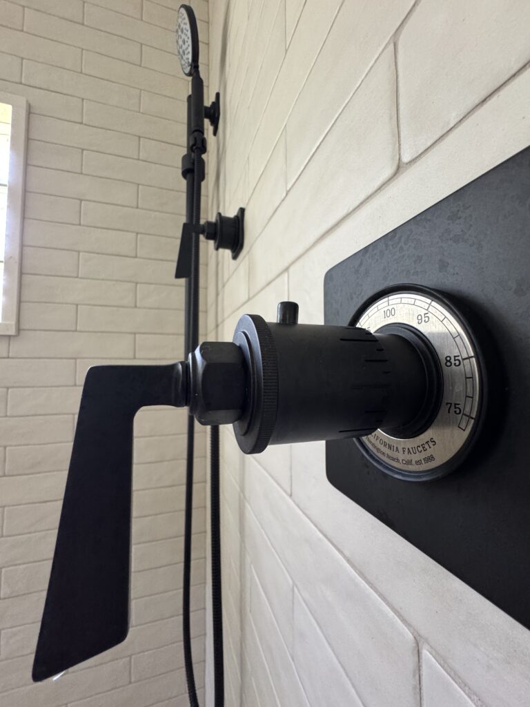 Close-up of a California Faucets Steampunk Bay thermostatic shower valve in matte black installed in a luxury master bathroom remodel in Woodstock, Illinois.