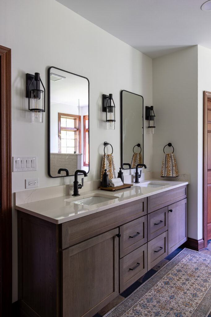 Custom Mouser bathroom cabinetry featuring the Amity door style in Hickory with a Peppercorn stain, Cambria Colton quartz countertops, and California Faucets fixtures in a luxury master bathroom remodel in Woodstock, Illinois