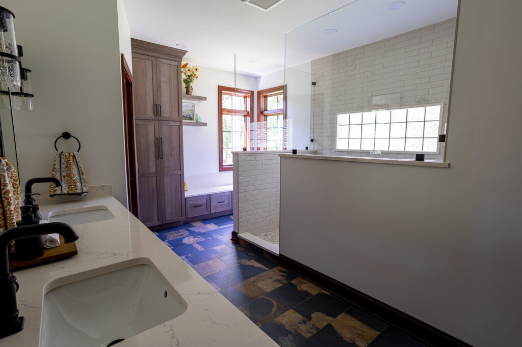 Luxury master bathroom remodel in Woodstock, Illinois featuring a custom walk-in shower, Mouser Hickory cabinetry, Cambria Colton quartz countertops, Marvin Elevate windows, built-in storage bench, and California Faucets fixtures.